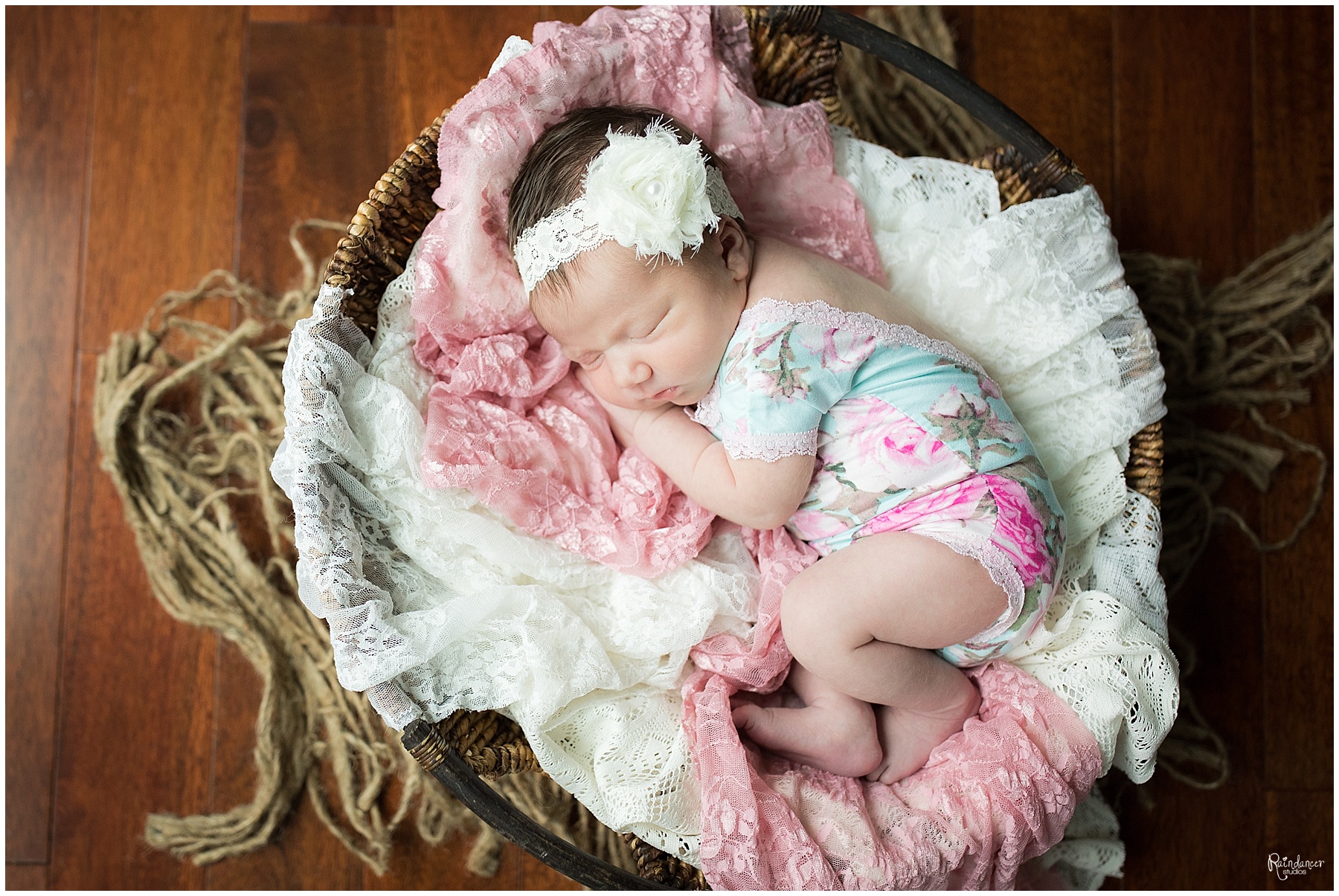 This newborn girl is in a basket with lace and a pretty bow during her newborn session in Indiana.