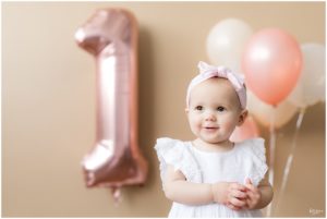 One year old baby girl in pink bow with balloons by Raindancer Studios Indianapolis Children Photographer Jill Howell