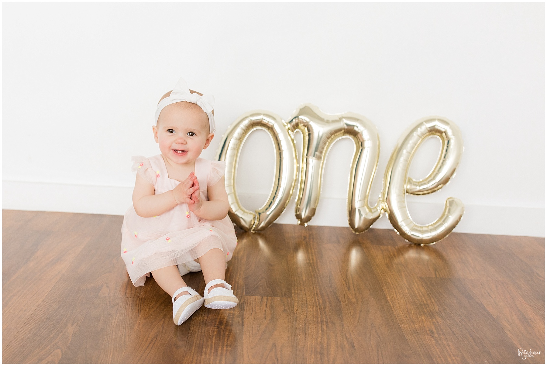 One year old baby girl smiling in a pink bow by Raindancer Studios Indianapolis Children Photographer Jill Howell