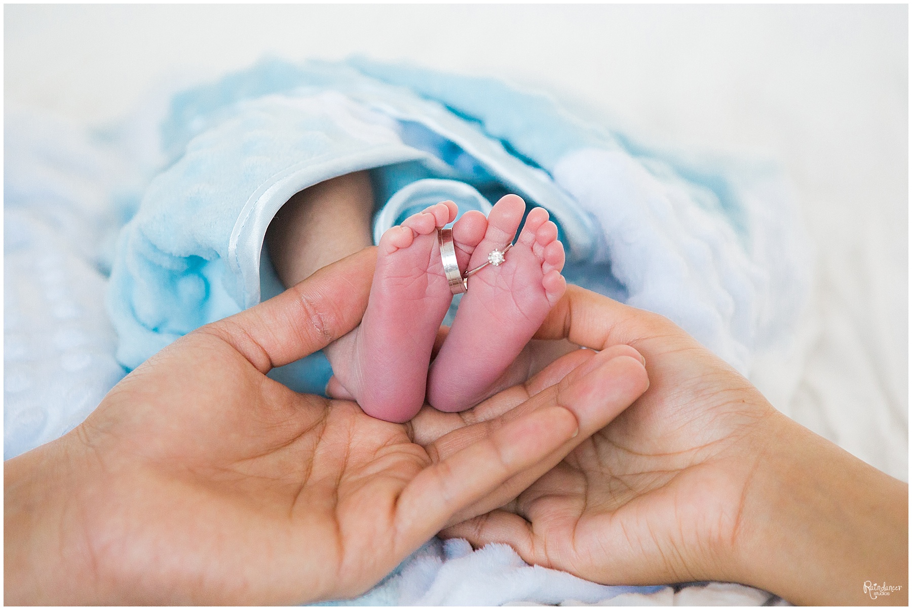 Parents holding newborn baby boy feet with parents wedding rings by Raindancer Studios Indianapolis Newborn Photographer Jill Howelll