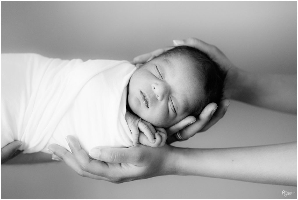 Newborn baby boy sleeping in parents hands by Raindancer Studios Indianapolis Newborn Photographer Jill Howell