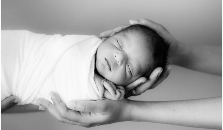 Newborn baby boy sleeping in parents hands by Raindancer Studios Indianapolis Newborn Photographer Jill Howell