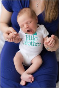 Mother in blue dress holding newborn baby boy in "big brother" onesie by Raindancer Studios Indianapolis Newborn Photographer Jill Howell