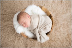 Newborn baby boy sleeping in a swaddle in a rustic bucket by Raindancer Studios Indianapolis Newborn Photographer Jill Howell
