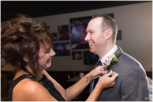 Mother of the groom putting on son's boutonniere by Indianapolis Wedding Photographer Jill Howell