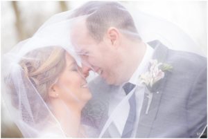 Bride and groom hugging and smiling under veil by Raindancer Studios Indianapolis Wedding photographer Jill Howell