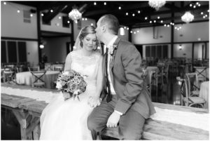 Groom kissing brides forehead while sitting on table by Raindancer Studios Indianapolis Wedding photographer Jill Howell