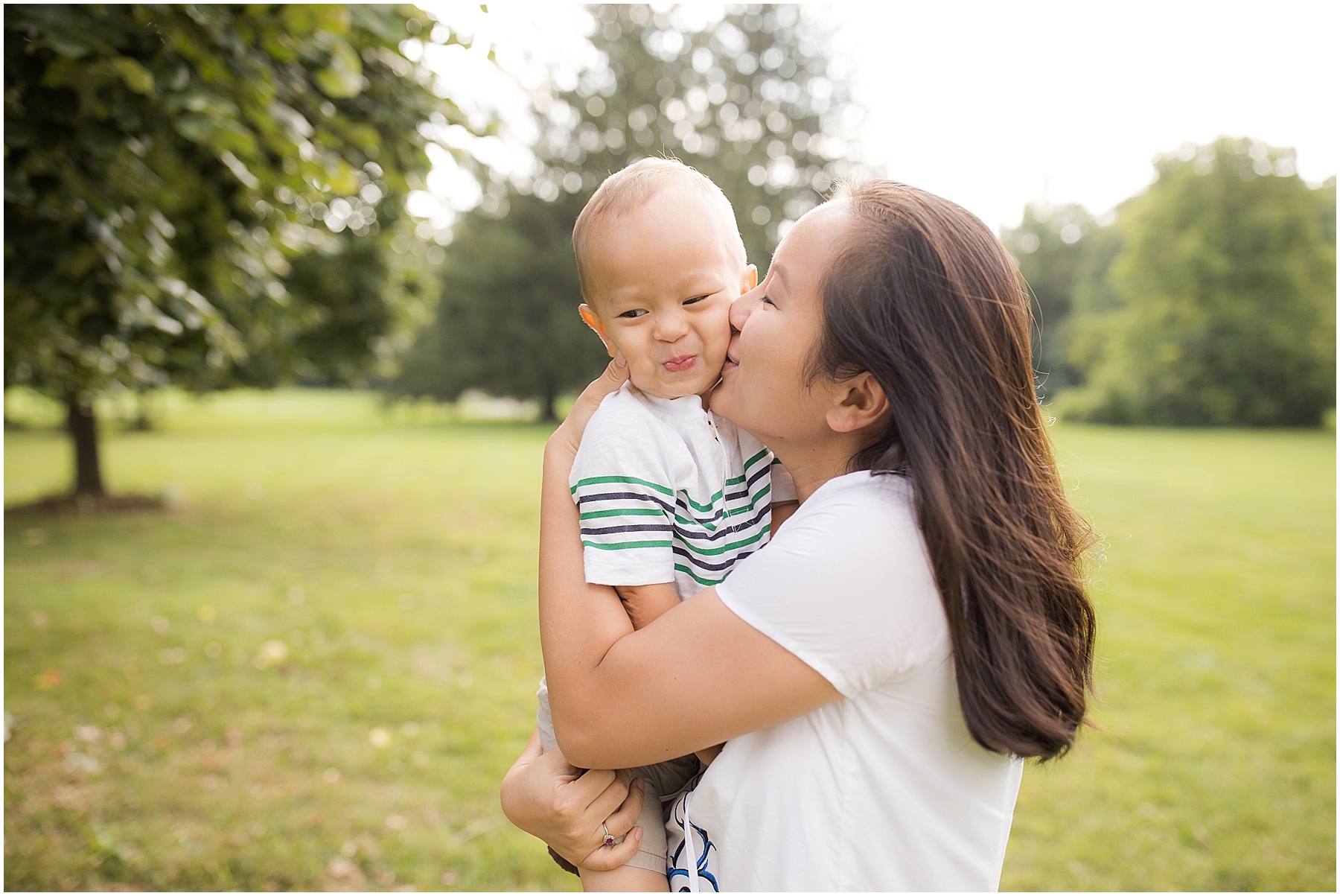 Mother kissing her little boy on the checks.  Indianapolis Family Photography, Raindancer Studios