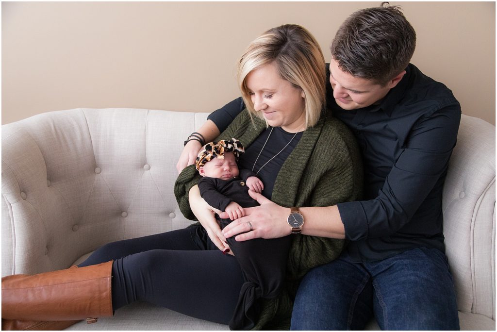 Family holding baby girl on couch. Taken by Indianapolis Newborn Photographer