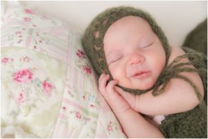 Smiling newborn girl with head on pillow. Indianapolis Baby Photography