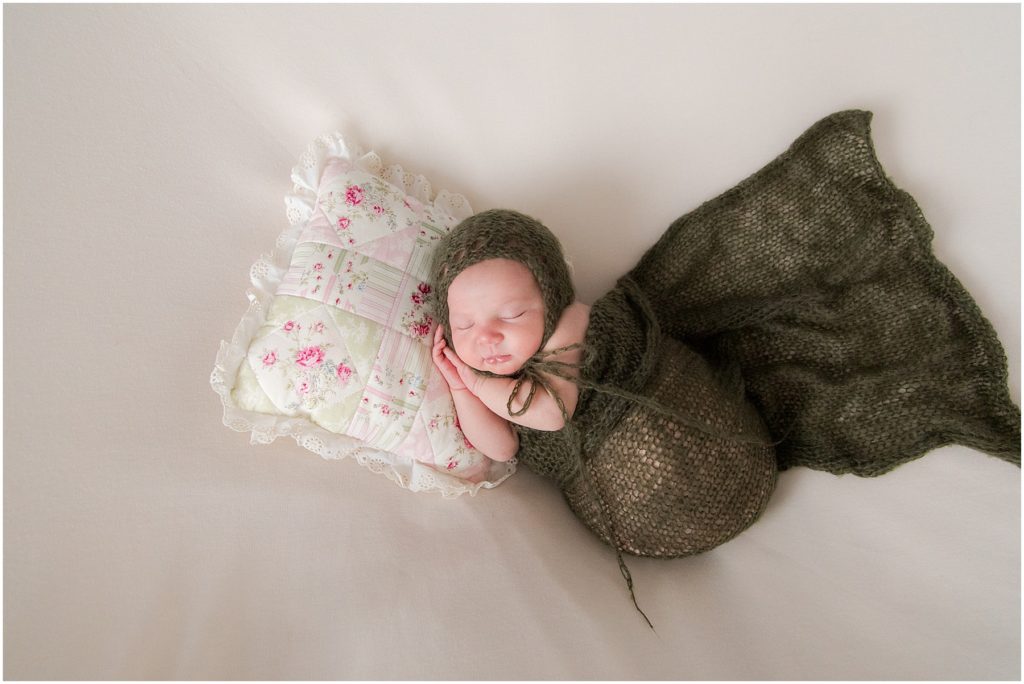 Newborn girl swaddled in olive blanket and on pillow. Raindancer Studios Newborn Photography