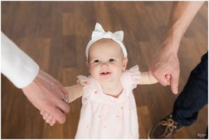 Parents holding hands with one year old baby girl by Raindancer Studios Indianapolis Children Photographer Jill Howell
